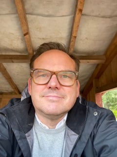 Kuva Kalle Eurosta. Hänellä on silmälasit, harmaa neule ja tumma takki.