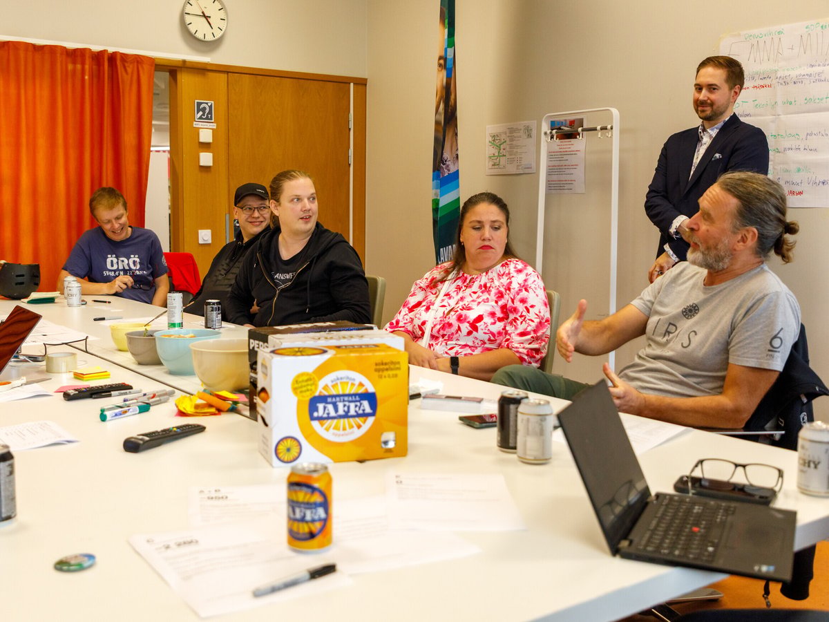 Campaign team members talking around a meeting table with laptops and papers, Lauri Lavanti standing at the back.