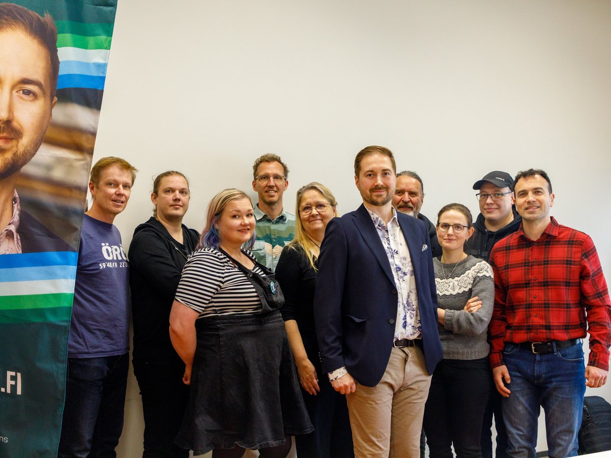 Ten members of the campaign team standing together in front of a campaign beach flag, Lauri Lavanti in the middle.