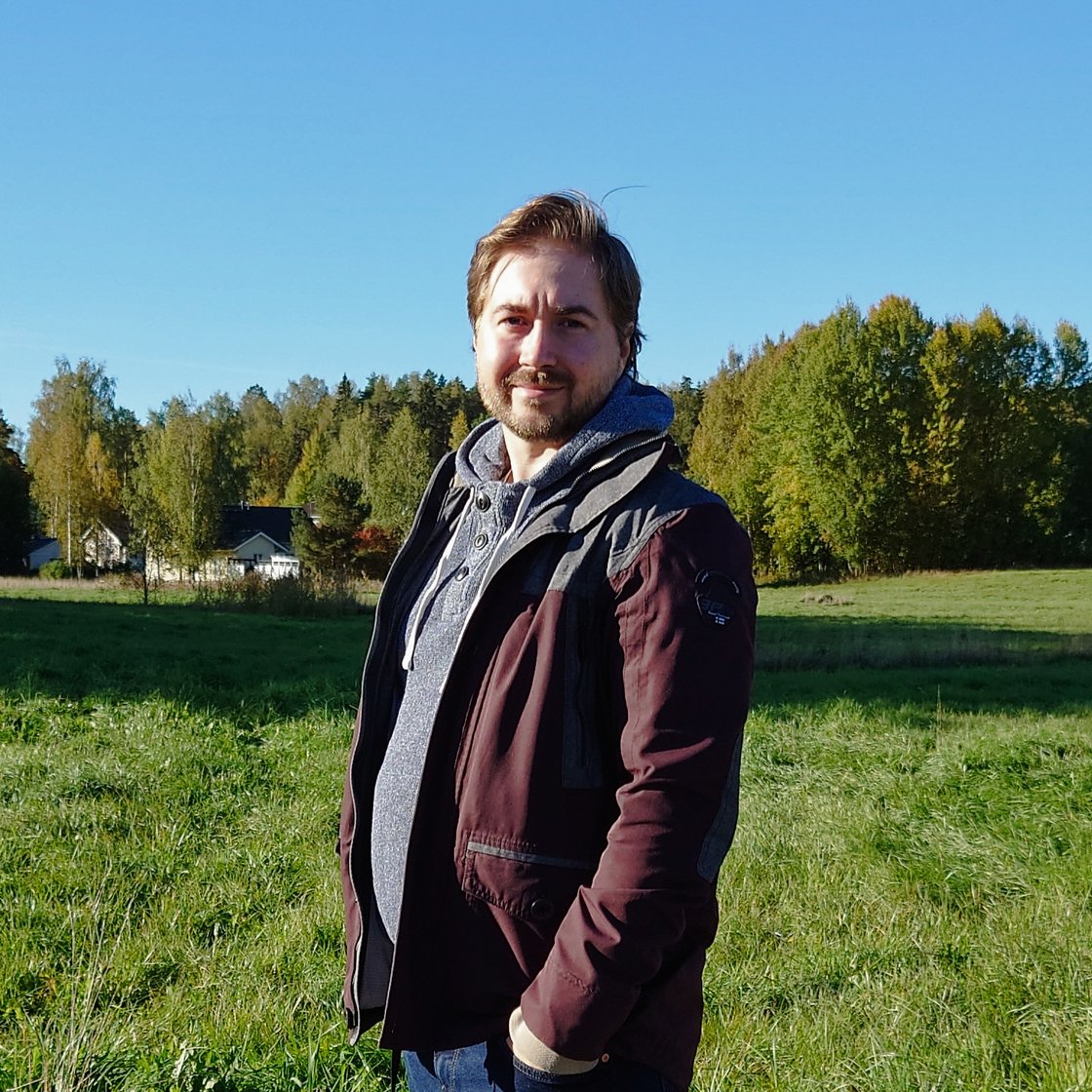 Lauri Lavanti standing in front of a field, with forest in the background.