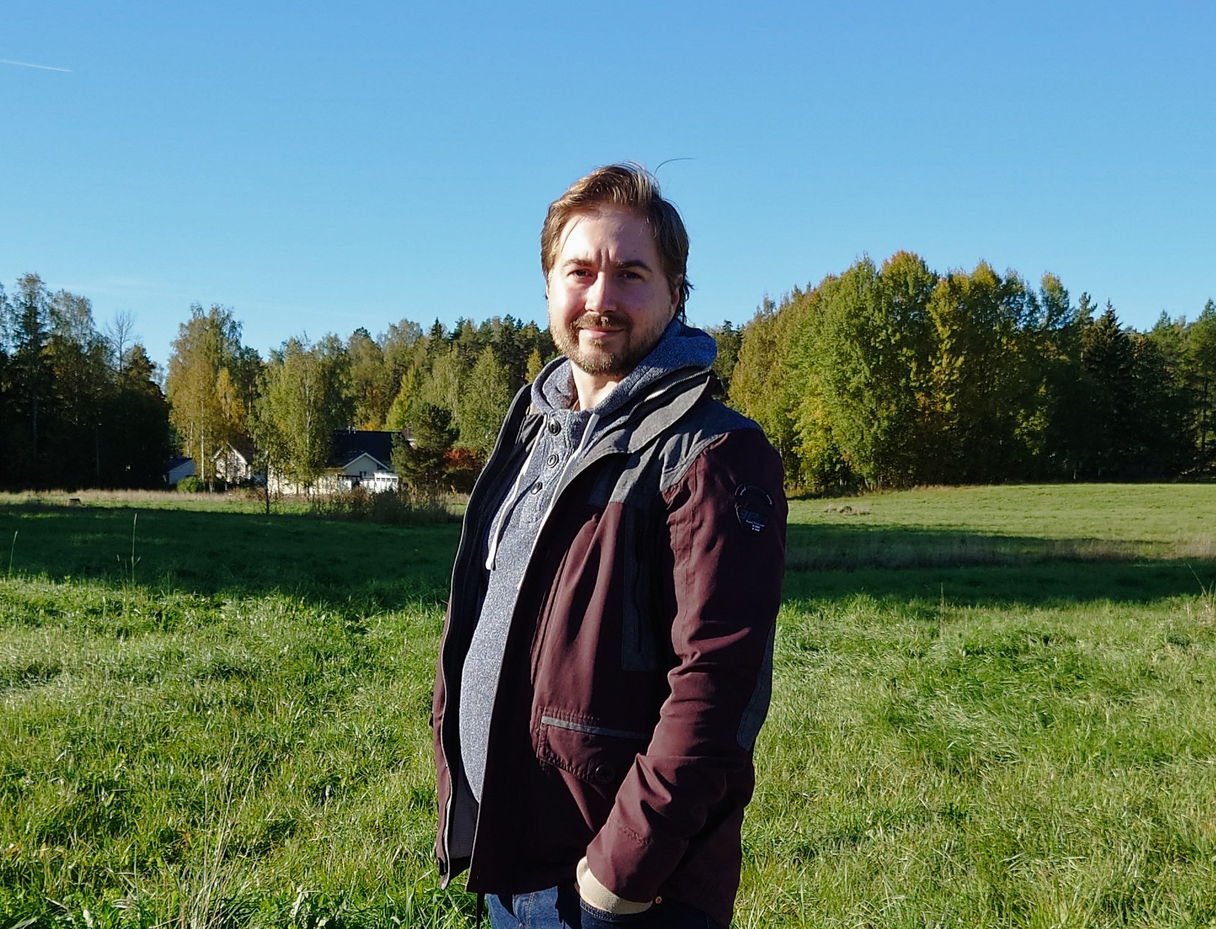 Lauri Lavanti standing in front of a field, with forest in the background.
