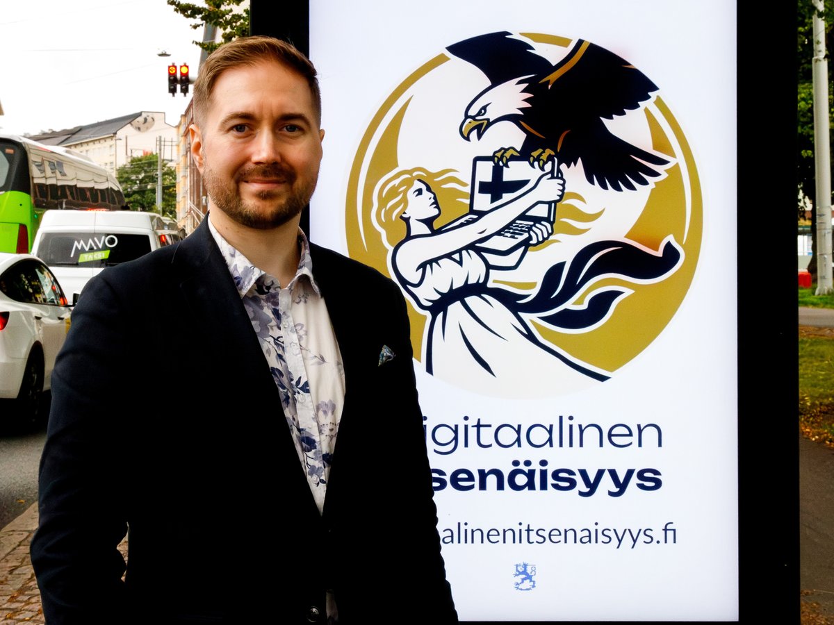 Lauri Lavanti smiling in front of a street billboard showing the Digital Independence citizens' initiative logo.