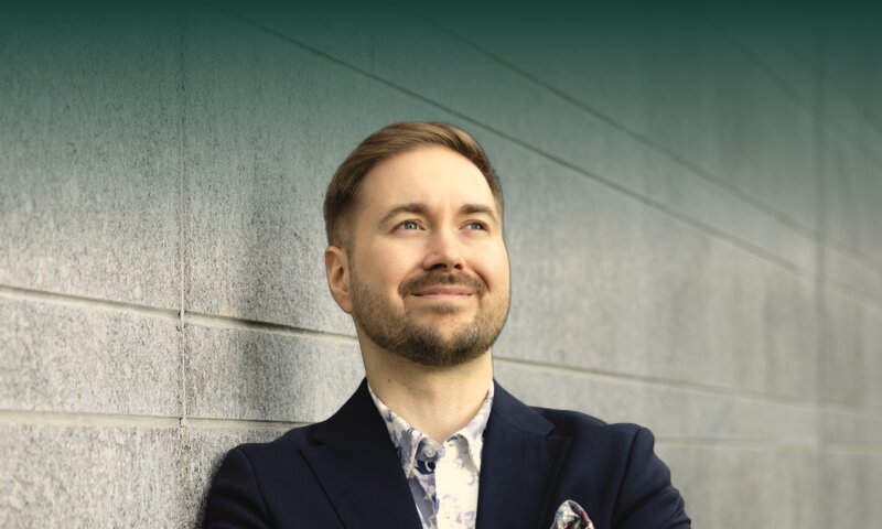 Lauri Lavanti nojaa graniittimuuriin kädet puuskassa ja katsoo ylöspäin, yllään tummansininen pikkutakki ja kukkakuvioinen paita.
