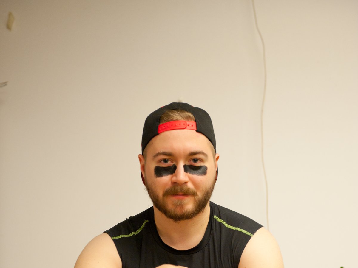 Lauri Lavanti with eye black and a backwards cap, hugging an American football against his chest.