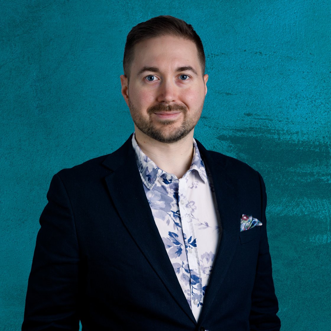 Lauri Lavanti standing in a floral shirt against a blue background