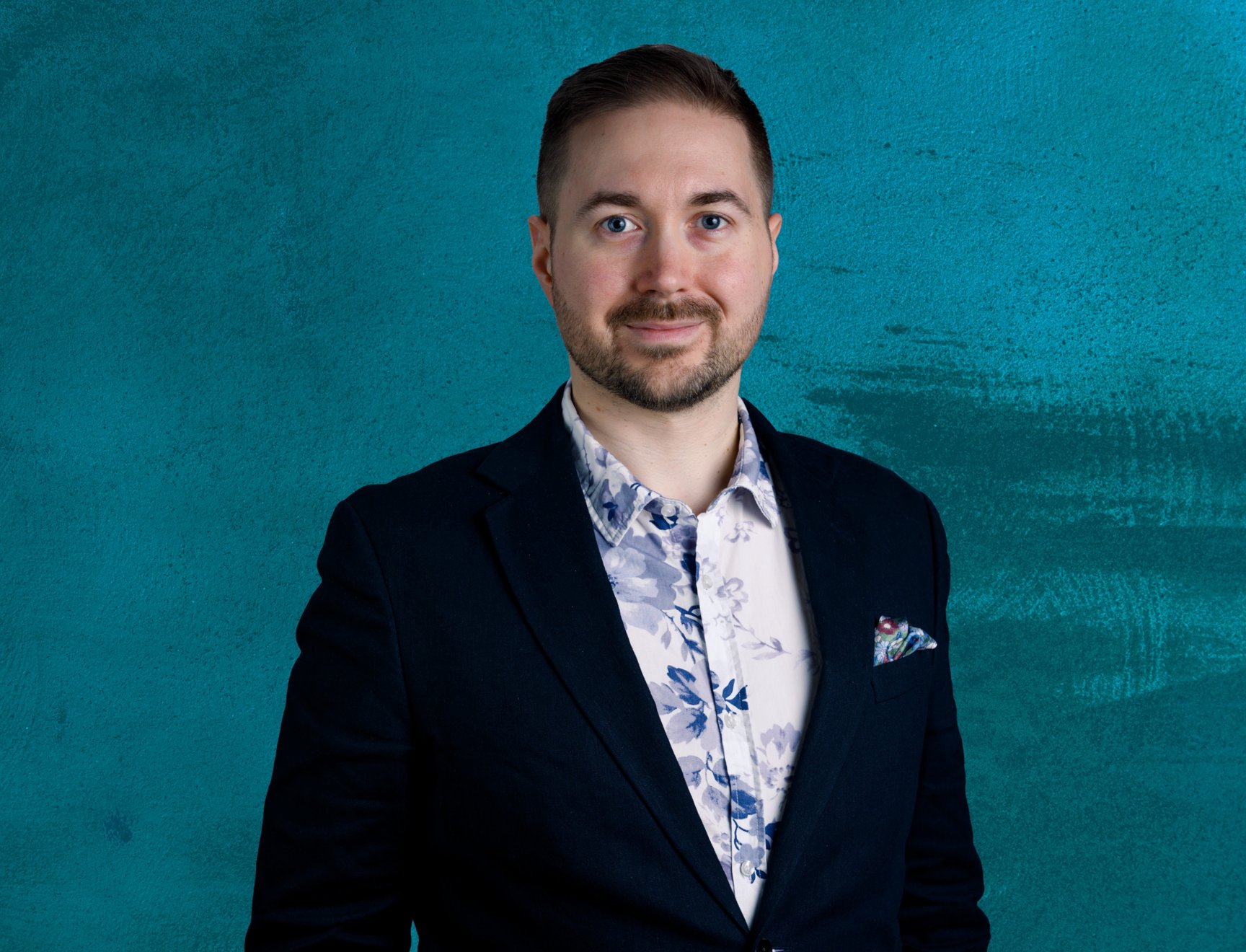 Lauri Lavanti standing in a floral shirt against a blue background