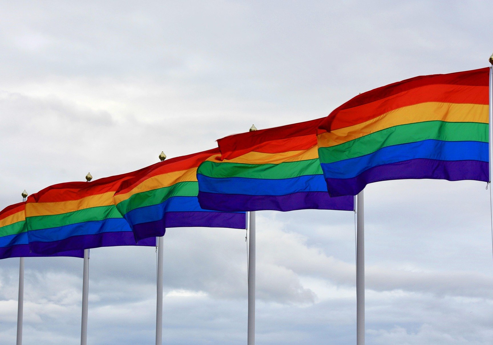 Several flagpoles with rainbow flags flying from them.