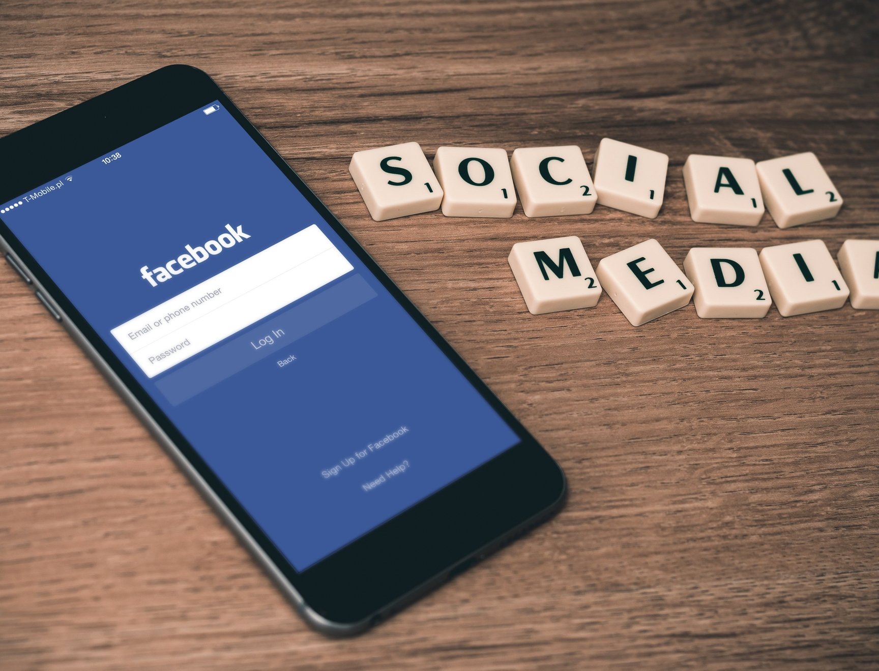 A phone with the Facebook app open waiting for login credentials, and the text "Social media" made from Scrabble tiles.
