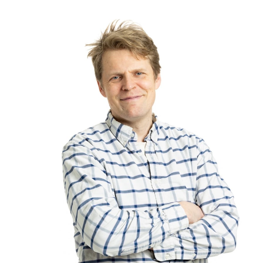 Kuva Ville Aarniosta. Hän hymyilee, ja hänellä on päällään sinivalkoruudullinen kauluspaita, kädet ristissä rinnan päällä.