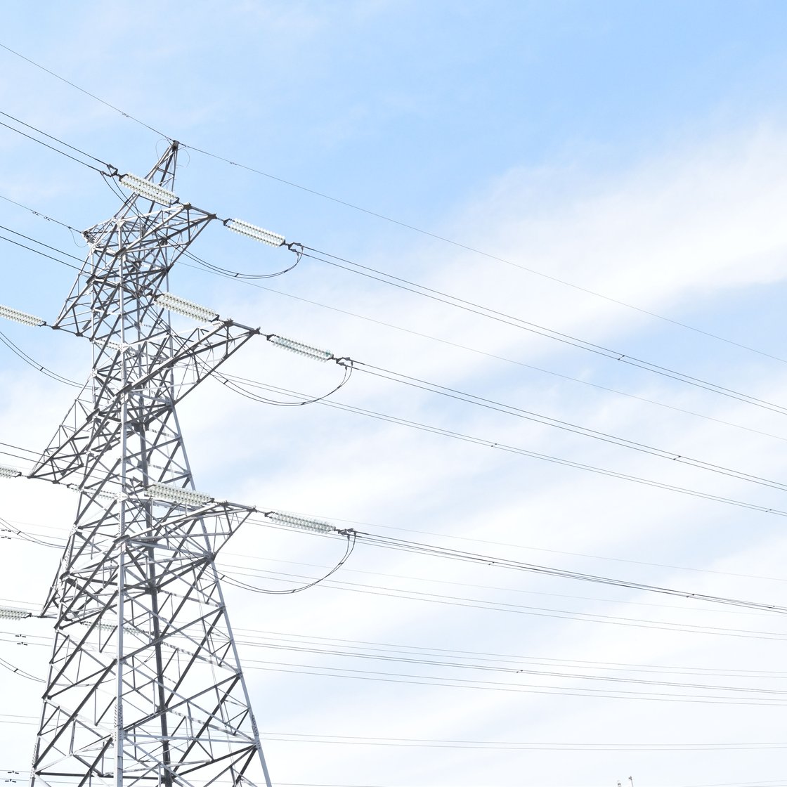 High-voltage power line pylons against a blue sky