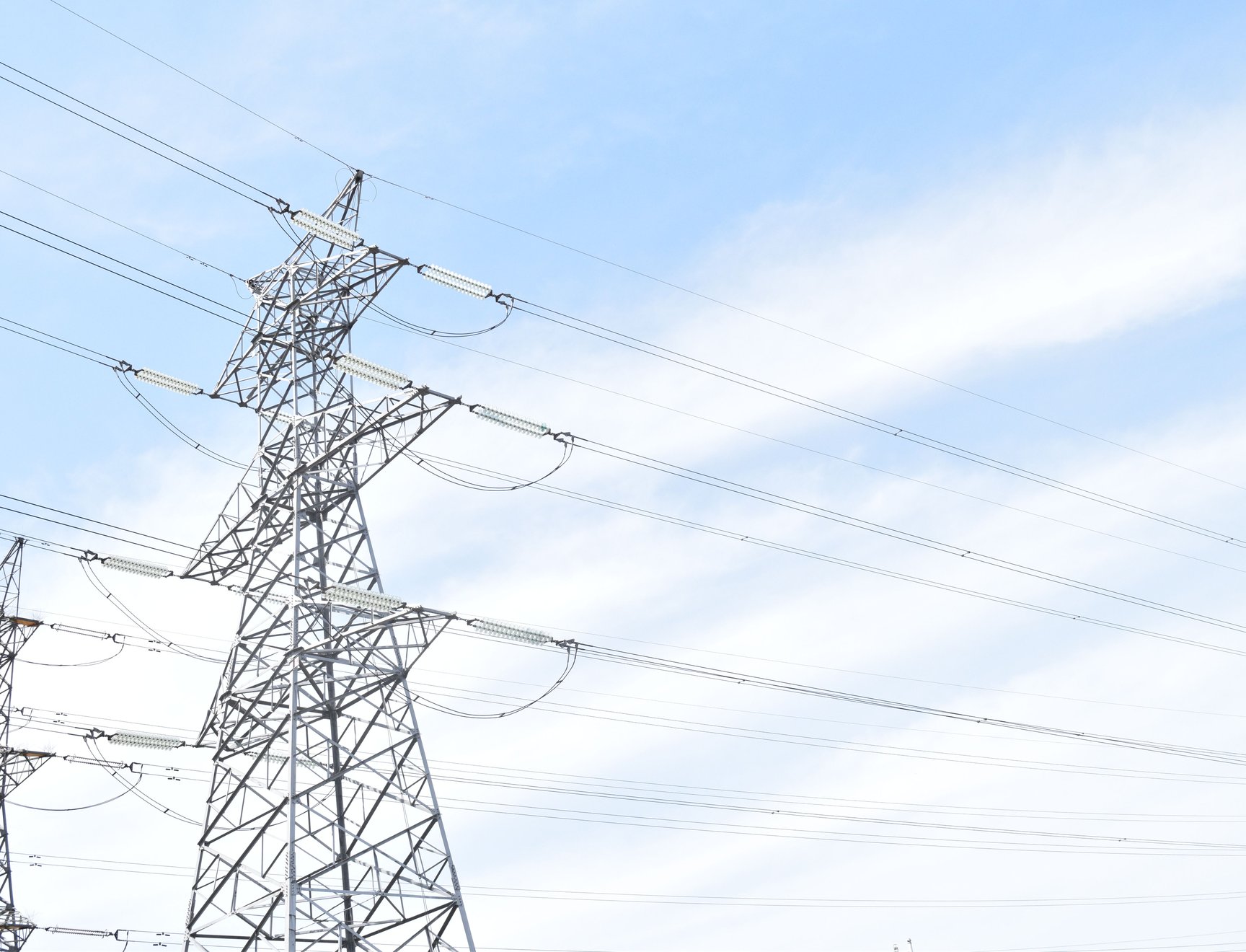 High-voltage power line pylons against a blue sky