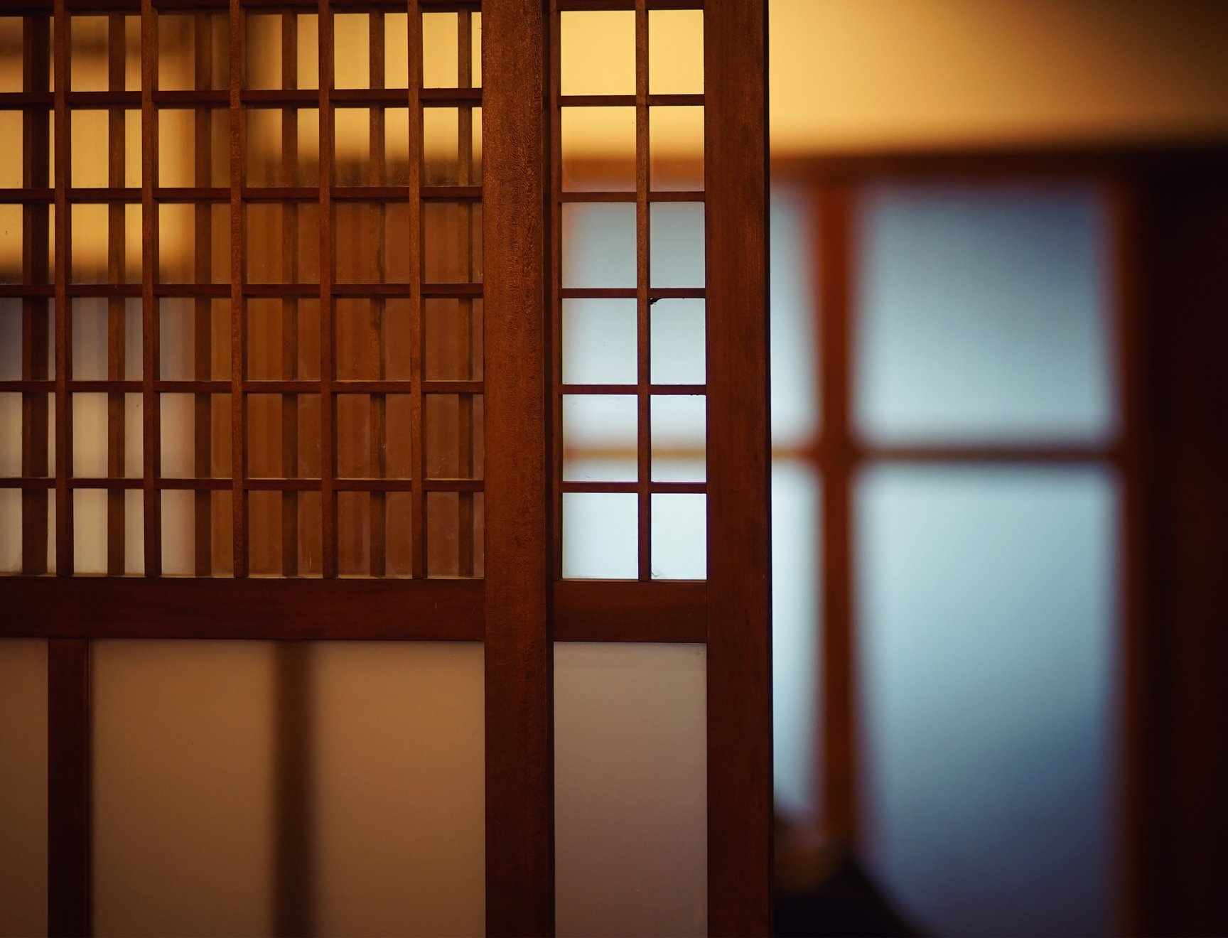 A Japanese-style screen behind which a room is visible in soft focus.