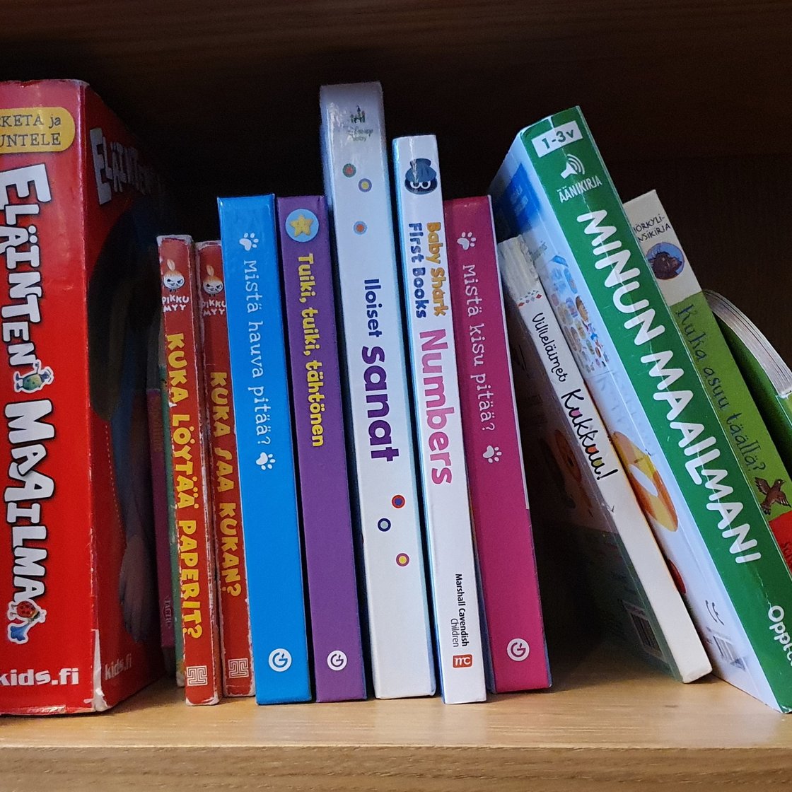 Several children's books on a bookshelf.