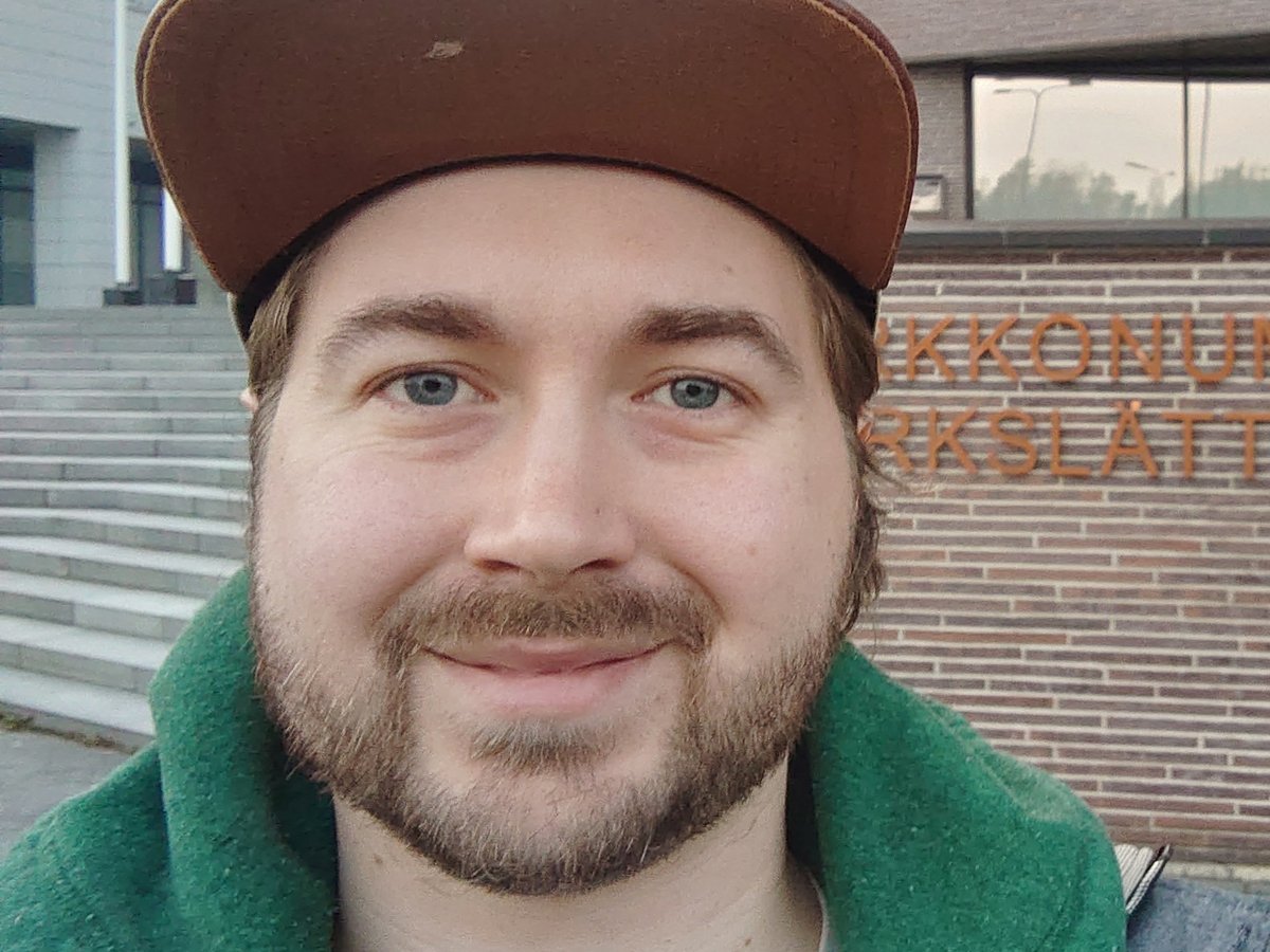 Close-up of Lauri Lavanti in a cap in front of the Kirkkonummi town hall sign.
