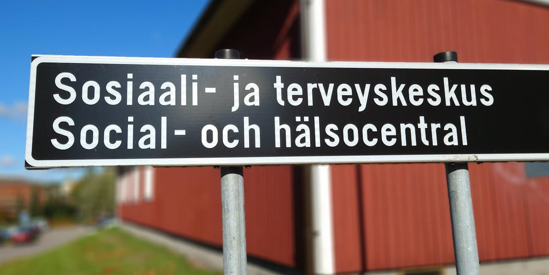 Kuva tiekyltistä, jossa lukee Sosiaali- ja terveyskeskus, sekä alla sama ruotsiksi, eli Social- och hälsocentral.