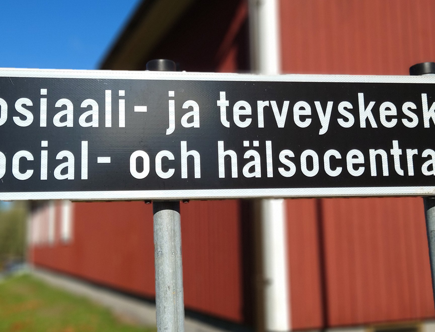 Kuva tiekyltistä, jossa lukee Sosiaali- ja terveyskeskus, sekä alla sama ruotsiksi, eli Social- och hälsocentral.