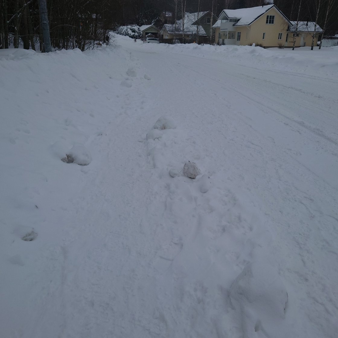 A poorly ploughed pavement beside a carefully ploughed road.