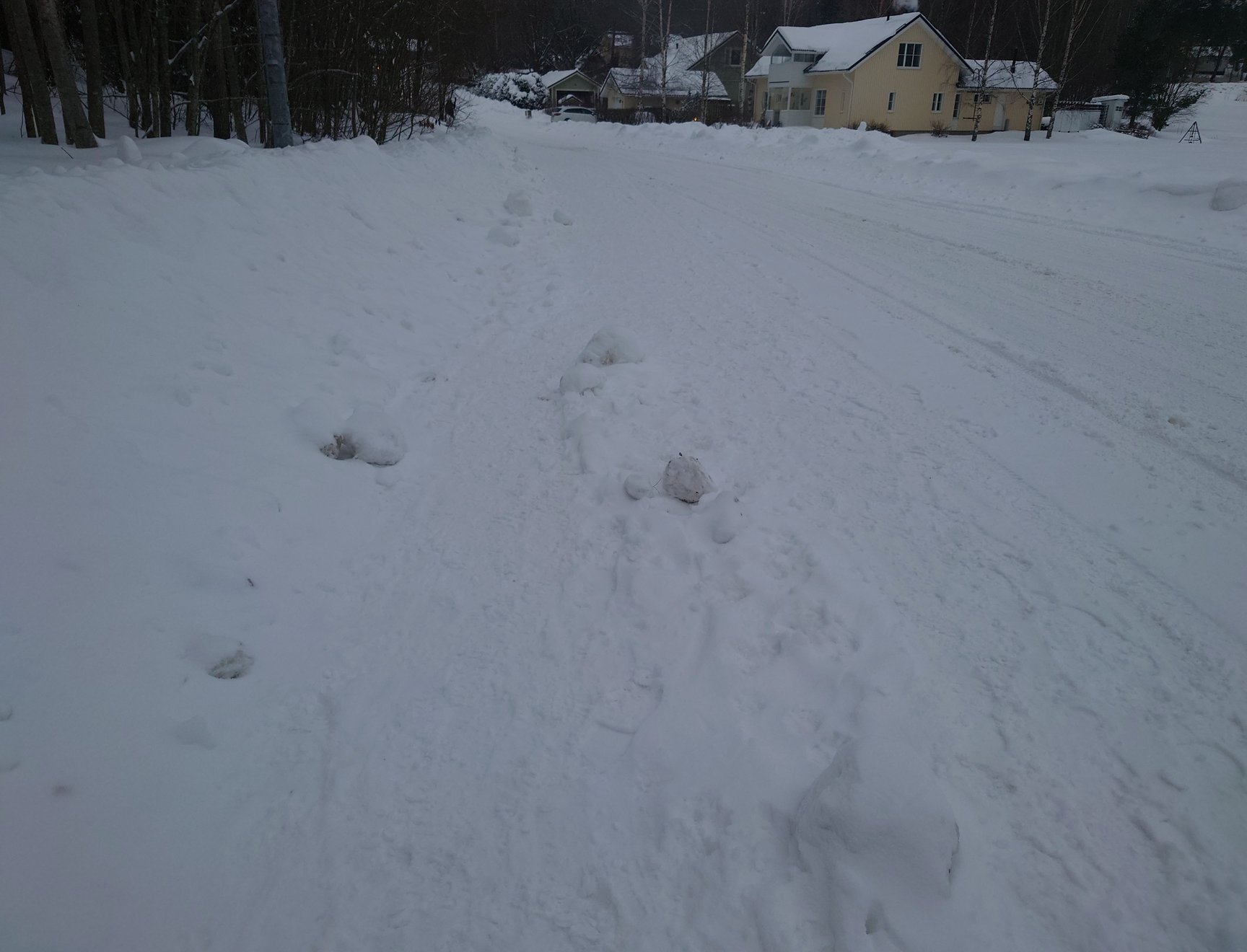 A poorly ploughed pavement beside a carefully ploughed road.